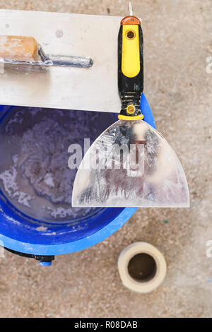 Eimer mit Gips und Metall Gebäude Spachtel. Über anzeigen und schließen. Stockfoto