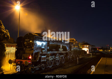 Lange Exposition, Night Shot von hinten beleuchtete, UK Dampflokomotive, die Übernahme von Wasser bei SVR-Station in der Dunkelheit. Atmosphärische als Dampf in den dunklen Himmel freigegeben. Stockfoto