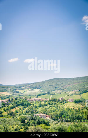 Vertikale Foto mit Blick in die schöne Toskana Landschaft. Mehrere Weinberge liegen zwischen Olivenbäumen Gassen. Typische Zypressen sind überall. Blauer Himmel mit Stockfoto