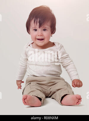 Foto der süße kleine Junge sitzt auf dem Boden, auf weißem Hintergrund, Kamera Stockfoto