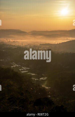 Nebel Dorf unter dem Hügel Leuchten von Sun mit warmen und gelbes Licht Stockfoto