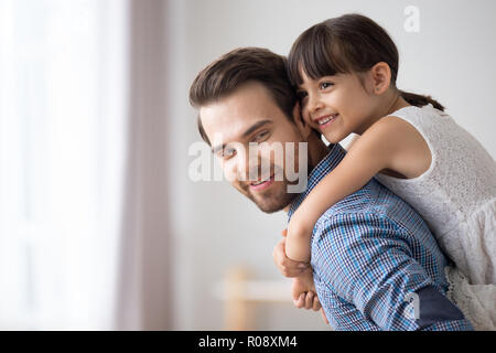 Vater hält Tochter piggyback stehen im Wohnzimmer. Stockfoto