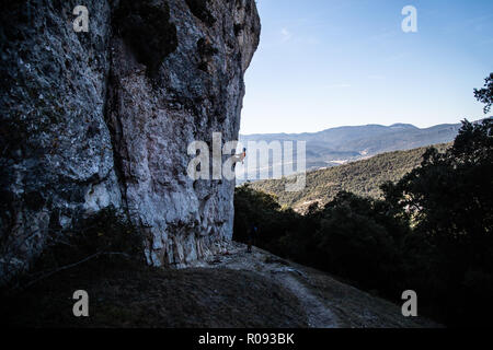 Junge Kletterer mann Klettern eine große Wand in einer schönen Landschaft im Schatten Stockfoto