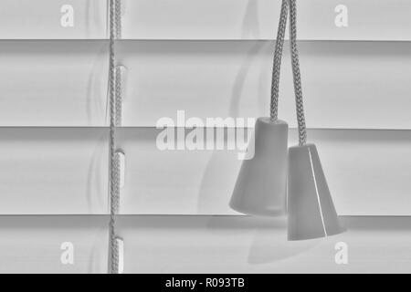Schwarze und weiße Makro Bild eines geschlossenen Jalousie Segment mit Zugschnur Quasten. Stockfoto
