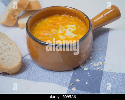 Hausgemachte leckere Karotten Suppe mit Eiern und Hafer, vegetarische Mahlzeit, fooblog Post, Brot auf dem Tisch, authentische Keramik Schüssel, gesunden Lebensstil, Mittag Stockfoto