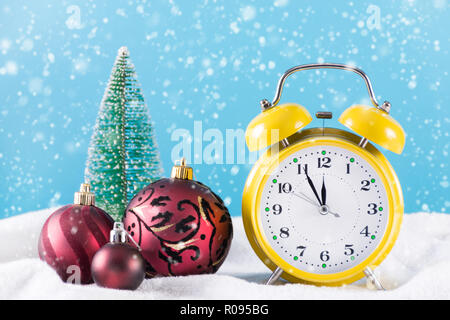 Christmas Ball Dekoration und retro Wecker auf Schnee und blauem Hintergrund. Winter Tag und Schneeflocken fallen. Neues Jahr und Weihnachten Konzept Stockfoto