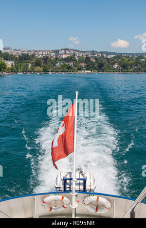 Fahrgastschiff mit Schweizer Flagge verlassen Lausanne Hafen von Ouchy am Genfer See (Genfer See), in der Schweiz am schönen Sommer sonnigen Tag Stockfoto