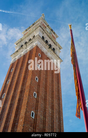 Campanile - Der Glockenturm von St. Mark's und ein Rot und Gold venezianischen Flagge auf der Piazza San Marco in Venedig, Italien Stockfoto