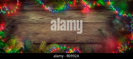 Weihnachten Lichterketten auf Holz. Weihnachten Hintergrund mit String Lichter und Kiefer. Tannenzweigen Stockfoto