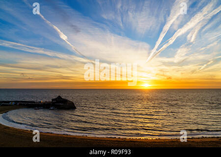 Sonnenaufgang über dem Strand und Hafen in Broadstairs in Kent. Dünne Band von Clear orange sky am Horizont mit blauem Himmel und Fetzen von dünnen weißen Wolken. Stockfoto