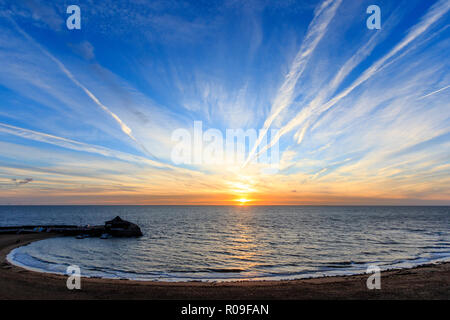 Sonnenaufgang über dem Strand und Hafen in Broadstairs in Kent. Dünne Band von Clear orange sky am Horizont mit blauem Himmel und Fetzen von dünnen weißen Wolken. Stockfoto