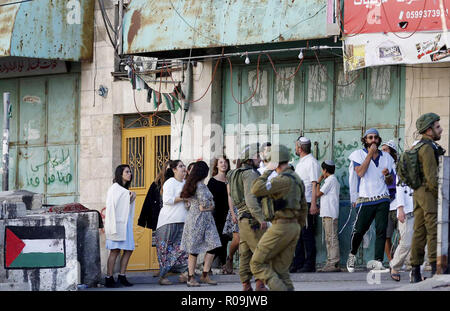 Hebron, West Bank, Palästina. 3. November, 2018. Israelische Soldaten stand Guard als jüdische Siedler Simchat Tora, eine jüdische Feiertag, der Abschluss der jährlichen Zyklus der öffentlichen Tora-lesungen Markierungen, die in der West Bank Stadt Hebron Am 3. November feiern, 2018 Credit: Wisam Hashlamoun/APA-Images/ZUMA Draht/Alamy leben Nachrichten Stockfoto