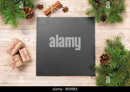Schiefer Tafel auf Holztisch mit Weihnachtsdekoration. schwarzer Schiefer Stein auf Holz- Hintergrund. kopieren. Neues Jahr Konzept. Stockfoto