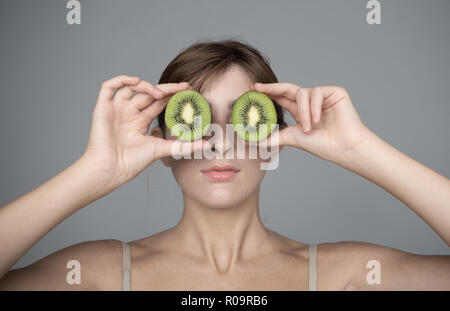 Verschiedene Ausdruck von jungen Mädchen mit Kiwi frisches Obst auf neutralem Hintergrund Stockfoto