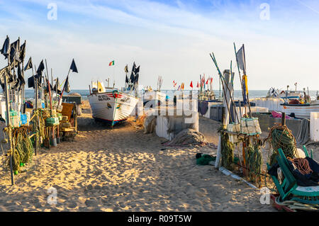 Lokalen Fischerboot von Fischen umgeben schwimmt auf der Strand von Monte Gordo, Algarve, Portugal in der Abendsonne Stockfoto