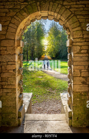 Ein paar gehen Hand in Hand im herbstlichen Sonnenschein in Cirencester Park, Gloucestershire. Stockfoto