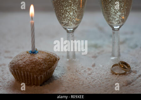 Zwei Gläser Champagner und Trauringe im Schnee Stockfoto