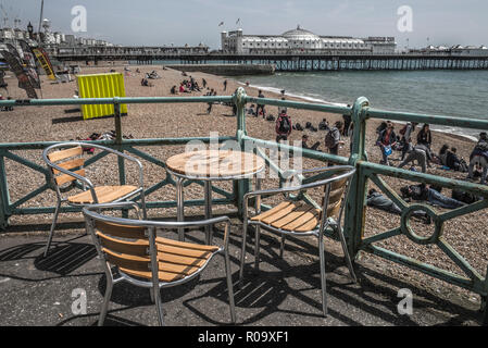 Leeren Tisch und Stühlen mit Blick auf Strand sceene auf Stein Strand Brighton UK Stockfoto