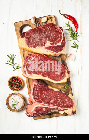 Rohes Fleisch Rindfleisch Steak. Black Angus Prime Fleisch - Ribeye, Roastbeef, T-Bone Steaks auf Schneidebrett. Ansicht von oben auf weißem Hintergrund. Stockfoto