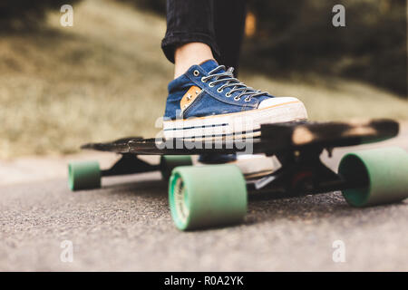 In der Nähe der Beine und Longboard stehen auf Asphalt Stockfoto