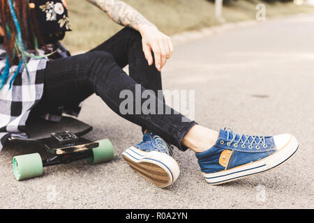 In der Nähe der Beine und Longboard stehen auf Asphalt Stockfoto