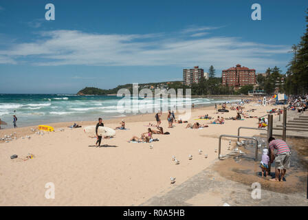 Blick auf den goldenen Strand von Manly Beach, Sydney, Australien mit Urlaubern Sonnenbaden, Schwimmen und Surfen in der Frühlingssonne. Stockfoto