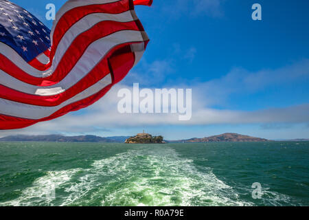 Alcatraz Island Bootsfahrt in der Bucht von San Francisco, California, United States. Fähre nach Alcatraz mit amerikanischer Flagge schwenken. Freiheit und Reisen anhand von quantitativen Simulatio Stockfoto