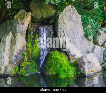 Schönen Wasserfall mit streaming Wasser mit großen Steinen und einige mit grünem Moos friedlichen Natur Landschaft Hintergrund Stockfoto