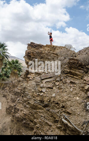 Fit aktive Frau Wanderer steht auf einer Klippe in Palm Springs Canyon trinkt ein Wasser an einem heißen Tag während einer Wanderung Stockfoto