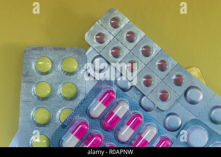 Gelbe Pillen, rote, weiße Tabletten in einem Paket auf gelbem Hintergrund Stockfoto
