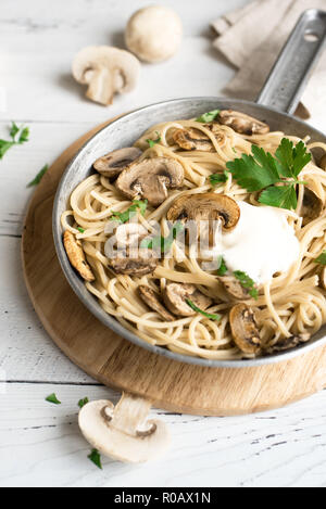 Pilz Spaghetti Pasta und Sauce auf weißem Hintergrund, Ansicht von oben. Hausgemachte italienische Pasta mit Champignon Pilze in der Küche pan. Stockfoto
