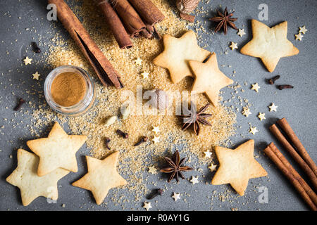 Weihnachten Gewürze, Lebkuchen und Plätzchen backen Zutaten auf grauem Beton Hintergrund. Zimt, Anis Sterne, Muskatnuss, Kardamom, Nelken, brauner Zucker Stockfoto
