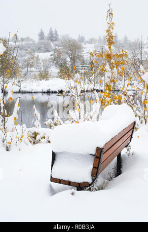 Schnee, der eine Bank in Prince's Island Park, Downtown Calgary, bei Schneefall Anfang Oktober zu brechen. Stockfoto