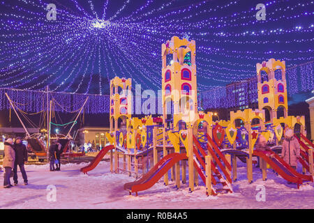 Kinderspielplatz im Winter unter dem Girlanden mit Beleuchtung auf das Neue Jahr Urlaub Stockfoto