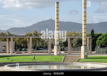 Menschen auf dem Weg über das Gras mit Hund am Placa d'Europa in Anella Olímpica de Montjuic, Barcelona, Spanien. Stockfoto