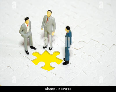 Geschäftsmann stand vor der fehlende Stück jigsaw auf dem gelben Hintergrund. Stockfoto