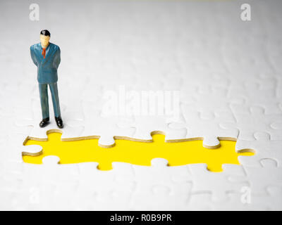 Geschäftsmann stand vor der fehlende Stück jigsaw auf dem gelben Hintergrund. Stockfoto
