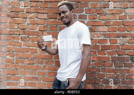 Der dunkelhäutige Mann im weißen T-Shirt, blank Business Card. Stockfoto