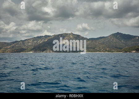 Gebirge in der Mitte des Meeres unter einem bewölkten Himmel gesehen. Stockfoto