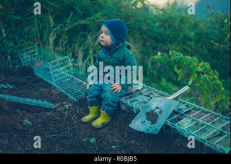 Ein kleines Kind sitzt auf einige gabians in einem Garten Stockfoto