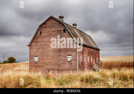 Eine alte rote Scheune steht neben einem Feld in der Palouse Landschaft in der Nähe von Oakesdale, Washington. Stockfoto