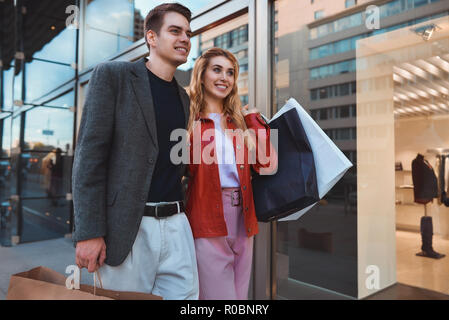 Schönes Paar mit Einkaufstüten spricht und lächelnd, während sie Shopping in der Mall konzentrieren sich auf die Frau Stockfoto