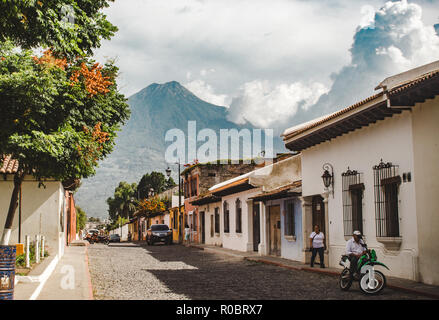 Typisch gepflasterten Straße in Antigua Guatemala an einem sonnigen Tag - Volcan Agua Vulkan über Häuser im Kolonialstil Stockfoto