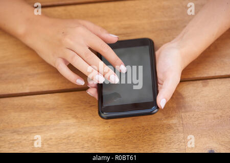 7/8 Schuß von der Frau Hand halten Handy und Sie auf den Bildschirm tippen. Stockfoto