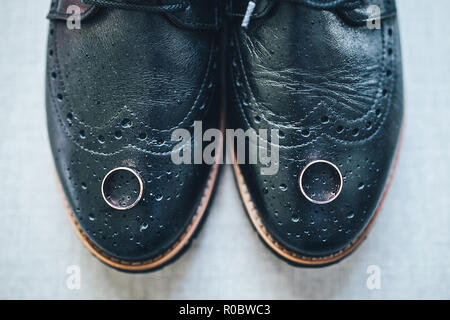 Trauringe liegen auf die Schuhe der Bräutigam Stockfoto