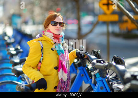 Glückliche junge Frau touristische bereit, ein Leihfahrrad in New York City an sonniger Frühlingstag zu fahren. Weibliche Reisende ihrer Zeit in Downtown Manhattan genießen. Stockfoto