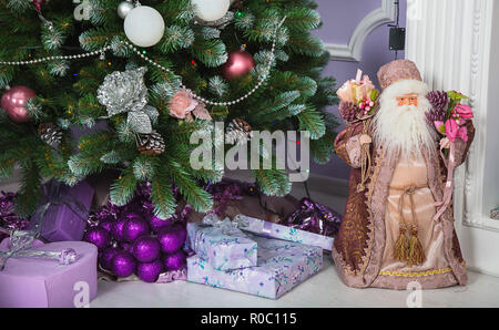 Santa Claus in der Nähe von Weihnachtsbaum mit Geschenken und einer Reihe von Kerzen auf dem Weihnachten und Neues Jahr Stockfoto