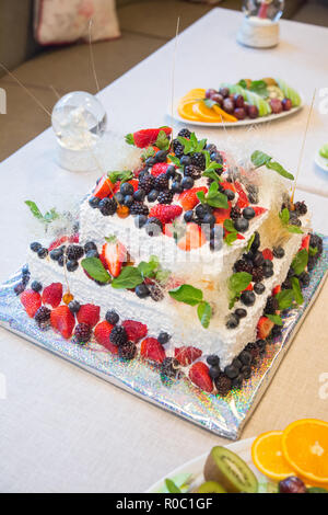 Foto eines festlichen multi-tiered Kuchen mit Beeren und Schokolade dekoriert Stockfoto