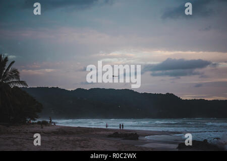 Drohne fliegt über den langen Sandstrand Paradise Strand von Playa del Carmen, Santa Teresa, Costa Rica bei einem farbenfrohen Sonnenuntergang Stockfoto