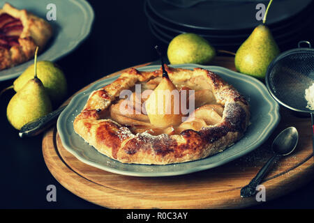 Hausgemachte Galette mit Birnen auf dunklem Hintergrund. Süße öffnen Obst Torte. Herbst Bäckerei. Ansicht von oben. Stockfoto